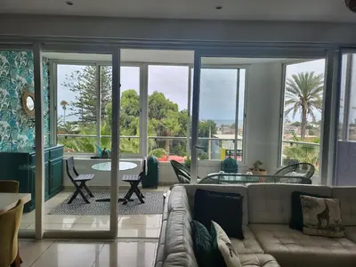 a living room with a couch and a table at Appartement Luxueux vue Mer dans Résidence avec piscines et jardin in Dar Bouazza