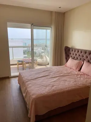 a bedroom with a large bed and a large window at Appartement de luxe à peninsula in Casablanca