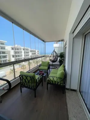 a balcony with two chairs and a table and windows at Appartement de luxe à peninsula in Casablanca
