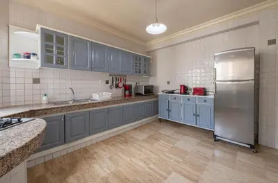 a kitchen with blue cabinets and a stainless steel refrigerator at Cosy Apartment 200 M2 Hay Ryad Rabat in Rabat