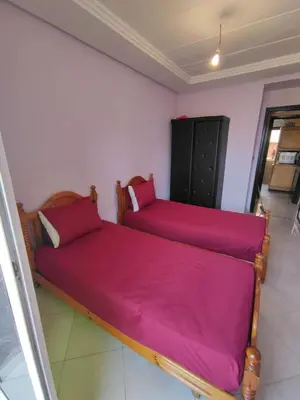 two beds in a room with pink sheets at Molto carino ben solare in Sidi Rahal
