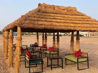a group of chairs under a straw umbrella on the beach at Residence Casa Bay Sidi Rahal in Sidi Rahal