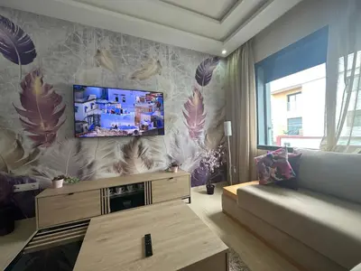 a living room with a couch and a tv on a wall at App à côté du parc et corniche in Mohammedia