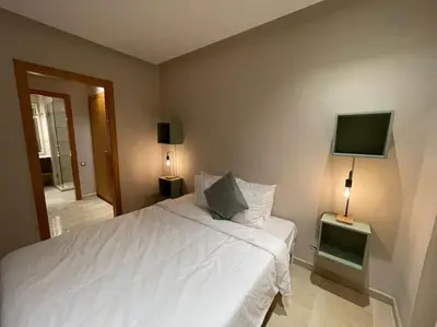 a bedroom with a white bed and a flat screen tv at Luxury Villa Oasis, Bouznika Bay in Bouznika