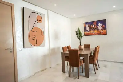 a dining room with a table and chairs and a painting at Luxury Prestigia 2Bed Rooms in Rabat