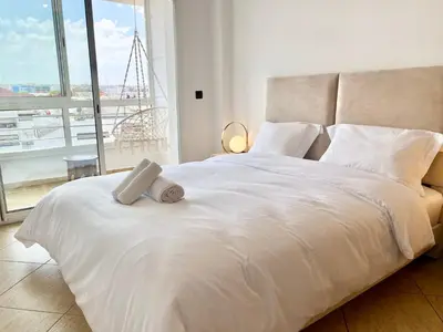 a bedroom with a white bed with a large window at Appartement au cœur de Rabat in Rabat