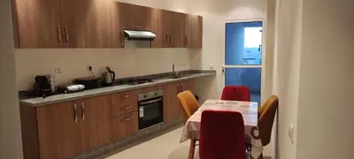 a kitchen with wooden cabinets and a table with red chairs at APPARTEMENT haut standing in O Ben Slimane
