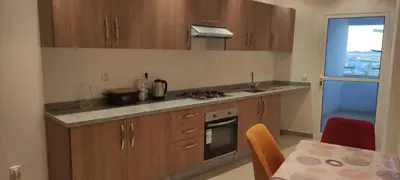a kitchen with wooden cabinets and a table with a tableablish at APPARTEMENT haut standing in O Ben Slimane