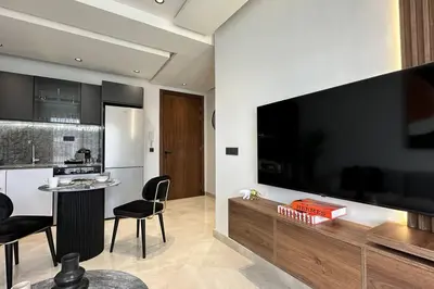 a living room with a large television and a kitchen at Top Floor Studio - By AppartAli in Casablanca