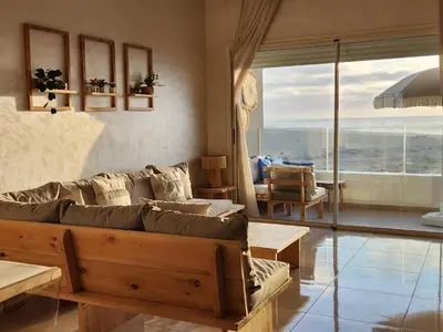 a living room with a couch and a view of the ocean at Sidi Rahal Blue View, Beachfront wide seaview with pool in Sidi Rahal