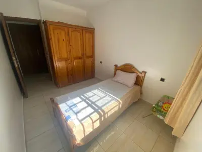 a small bedroom with a bed and a wooden cabinet at Appartement avec suite parentale in Mohammedia