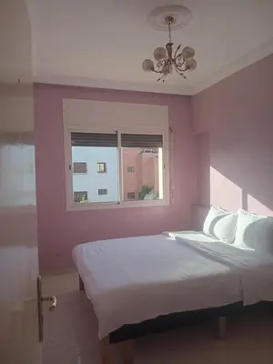 a bedroom with a bed with a pink wall and a window at Appartement HASSANIA in Casablanca