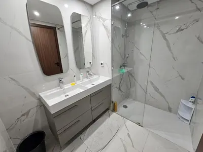 a white bathroom with a sink and a shower at Superbe Appartement Green Town in Oulad Lahsene