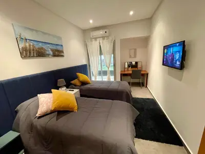 a bedroom with two beds and a tv on the wall at Au Cœur Des Sables D’or - Harhoura in Temara
