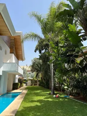 a yard with a swimming pool next to a house at Belle Villa à Bouznika plage - Golf Bouzbay in Bouznika