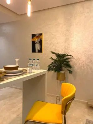 a yellow chair sitting next to a table with a plant at Glamorous Habous - By AppartAli in Casablanca