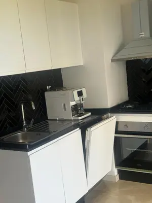 a kitchen with white cabinets and a sink at Le Carrousel Appartement in front of the see in Rabat