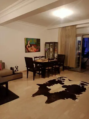 a living room with a table and chairs and a rug at Bel appartement à skhirat plage et à 20 mn de Rabat in Skhirat