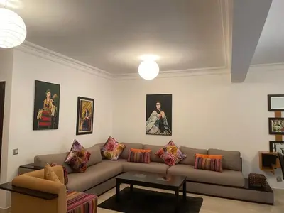 a living room with a couch and paintings on the wall at Bel appartement à skhirat plage et à 20 mn de Rabat in Skhirat