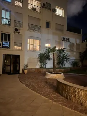 a building with a palm tree in front of it at Appartement Cozy au Triangle d’or in Casablanca