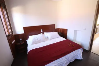 a bedroom with a large bed with red and white sheets at Villa Tizra - Guest house in AÃ¯n el Ksob
