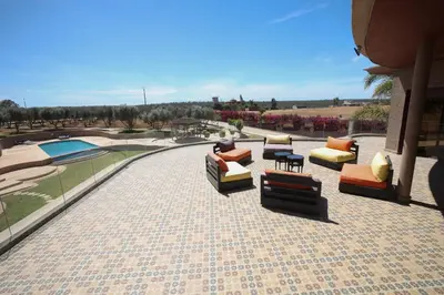a patio with couches and chairs and a pool at Villa Tizra - Guest house in AÃ¯n el Ksob