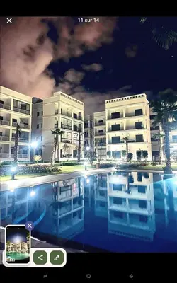 a swimming pool in front of a hotel at night at Idéal séjour Cozy aprt bouznika piscine et plage in Bouznika