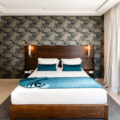 a bedroom with a large bed with blue sheets at Fourteen Hotel Ain Sebaa in Casablanca