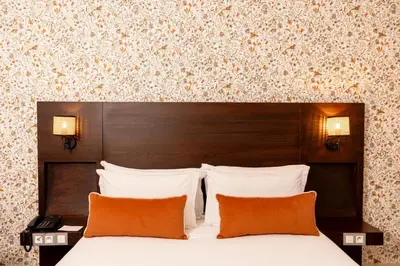 a hotel room with a bed with two orange pillows at Fourteen Hotel Ain Sebaa in Casablanca