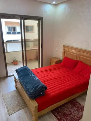 a bedroom with a red bed with a red blanket at Chez Soad in Bouznika
