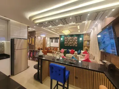 a kitchen with a bar with a couch and a tv at Grand Appartement corniche in Casablanca