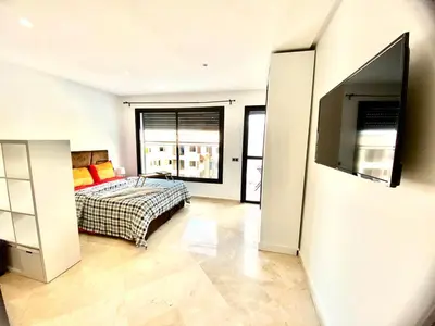 a bedroom with a bed and a flat screen tv at Quiet Top-Floor Studio by Med Faculty & Tram Lines in Casablanca