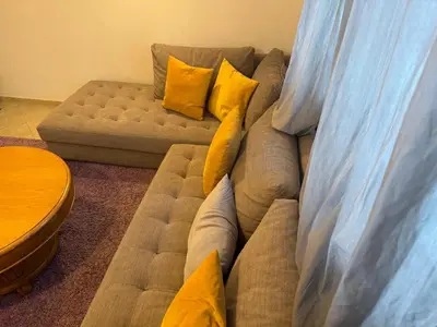 a couch with yellow pillows sitting next to a chair at Camilia Appart 2P TGV in Rabat