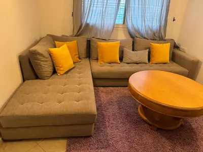 a couch with yellow pillows and a wooden table at Camilia Appart 2P TGV in Rabat