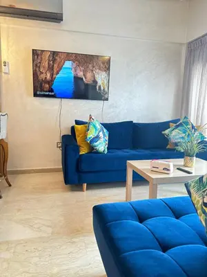 a living room with a blue couch and a table at Appartement confortable et pas cher au parc in Mohammedia