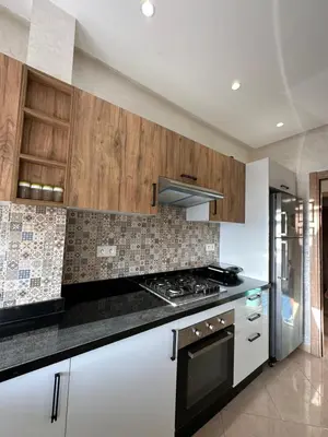 a kitchen with white cabinets and a stove top oven at Apparemment de luxe Bouznika in Bouznika