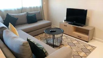 a living room with a couch and a flat screen tv at Beautiful apartment next to airport Mohamed V in Derroua