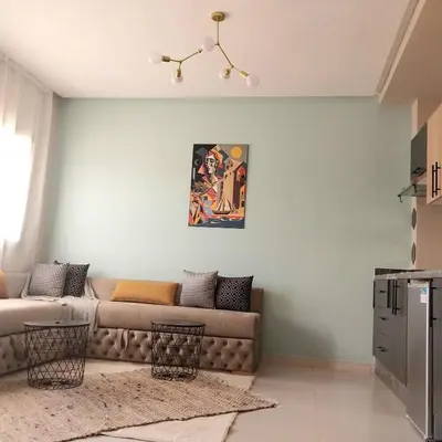 a living room with a couch and a painting on the wall at appartement moderne proche aéroport in Derroua