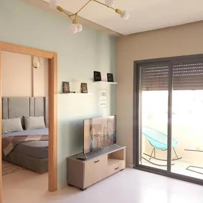 a bedroom with a bed and a tv and a balcony at appartement moderne proche aéroport in Derroua