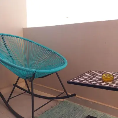 a blue chair next to a bench with a bowl on it at appartement moderne proche aéroport in Derroua