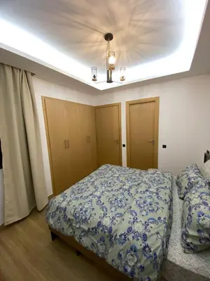 a bedroom with a bed with a blue and white comforter at Belle appartement à découvrir in El Harhoura