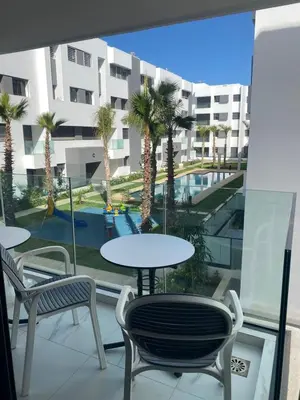 a balcony with tables and chairs and a view of a building at Belle appartement à découvrir in El Harhoura