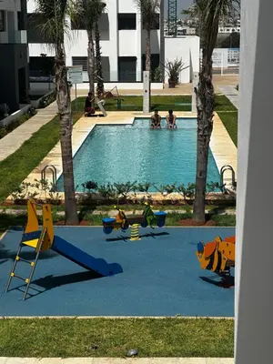 a pool with a playground with people playing in it at Belle appartement à découvrir in El Harhoura