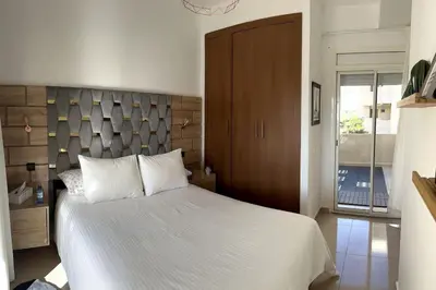 a bedroom with a large white bed with a wooden headboard at Vague Bleue chez Makuja Home in Bouznika