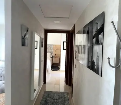 a hallway leading to a bedroom with white walls at Vague Bleue chez Makuja Home in Bouznika