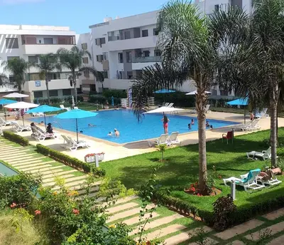 a swimming pool with people in a resort at Résidence de vacances vue piscine plages Mimosas Sablettes in Mohammedia
