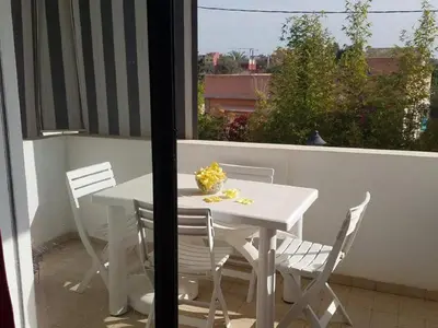 a white table and chairs on a balcony with a window at Résidence de vacances vue piscine plages Mimosas Sablettes in Mohammedia