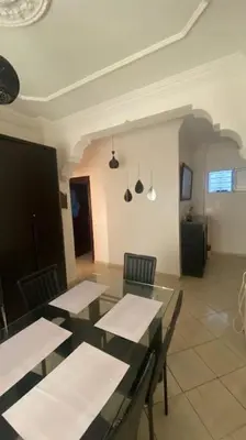 a dining room with tables and chairs in a room at Naj'Appart TEMARA WIFAK CALME SITUÉ PRÉS DE LA GARE FERROVIAIRE 4 MIN A PIED in Temara