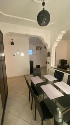 a dining room with a black table and chairs at Naj'Appart TEMARA WIFAK CALME SITUÉ PRÉS DE LA GARE FERROVIAIRE 4 MIN A PIED in Temara