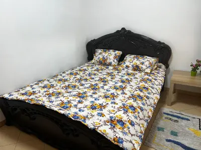 a bed with a floral comforter and two pillows at Appart à 2 min de Casanearshore in Casablanca